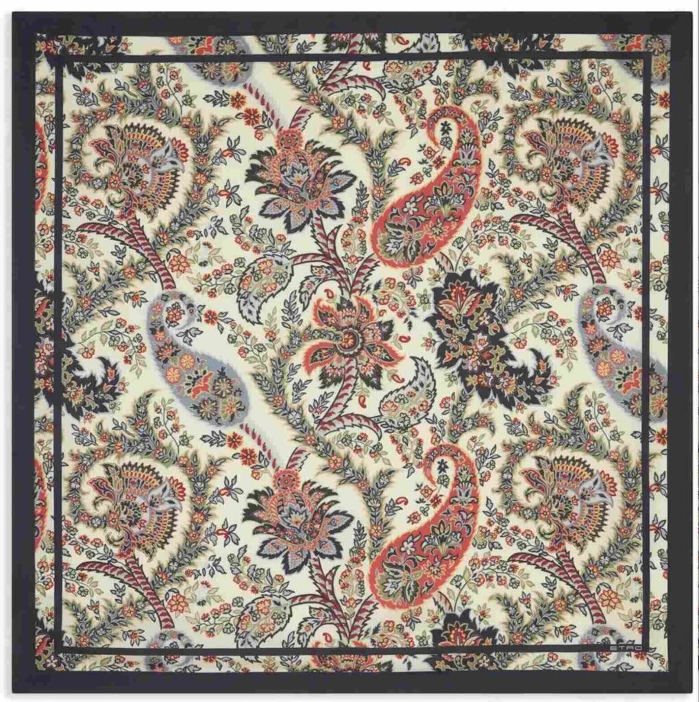 A top-down view of a square Docsun silk scarf laid flat, featuring a cream background filled with intricate red, olive green, and navy vintage paisley patterns, enclosed by a solid black border.
