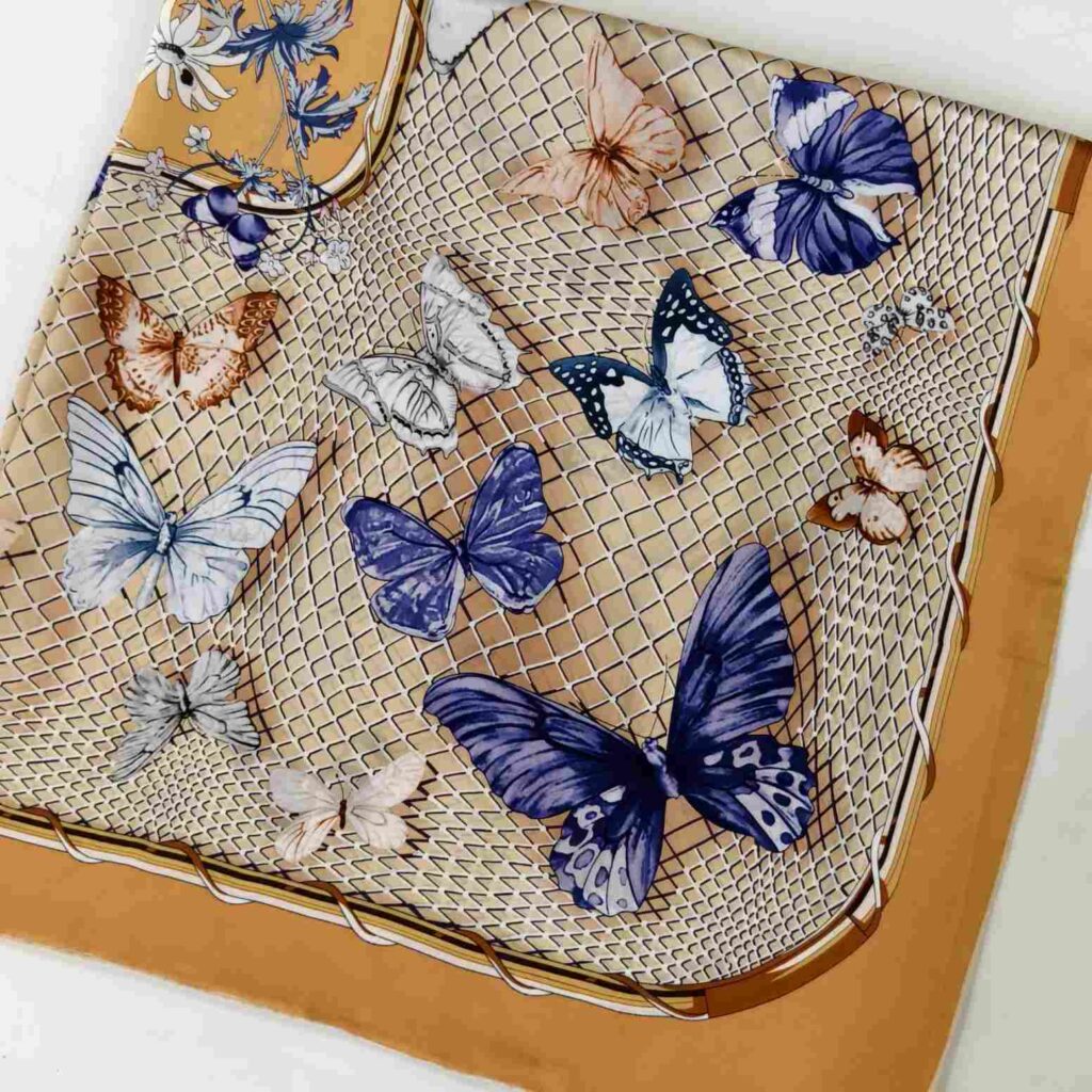 100% mulberry silk scarf with butterfly print, beige lattice pattern, and mustard yellow border.