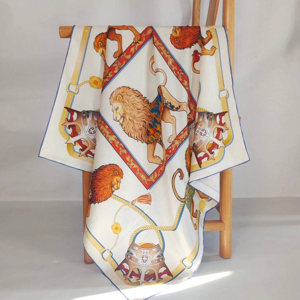 90cm custom 18mm twill silk square scarf featuring double-sided print and hand-rolled edges, with vintage lion and knight helmet patterns, draped over a wooden chair.