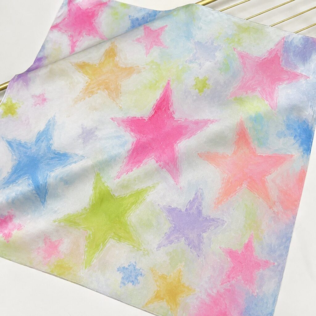 100% mulberry silk scarf with pastel five-pointed star print in pink, blue, green, yellow, and lavender tones.